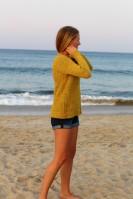 Женский пуловер связан спицами из пряжи выразительного желтого цвета